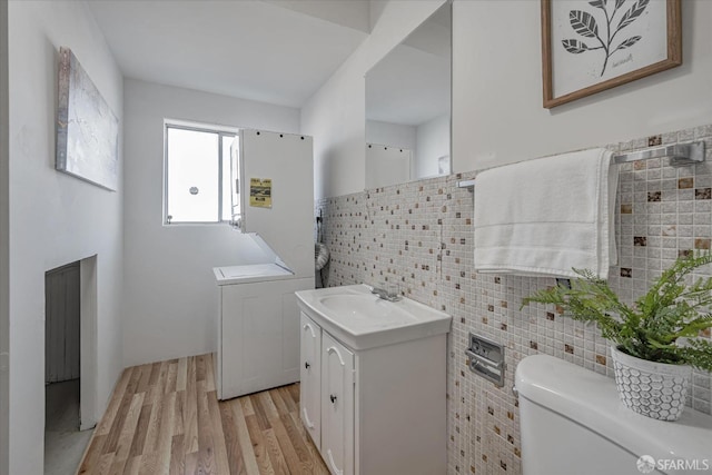 laundry area featuring laundry area, light wood-style flooring, a sink, and tile walls