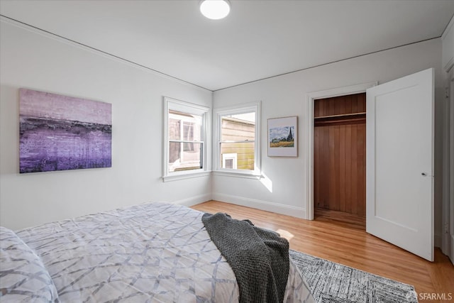 bedroom with baseboards, a closet, and light wood-style floors