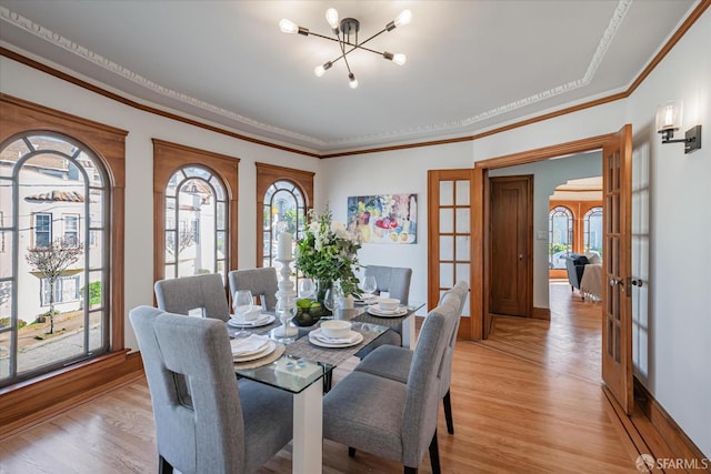 dining room with light wood-style floors, a chandelier, crown molding, and french doors