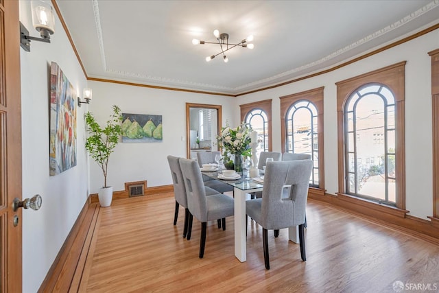 dining area featuring crown molding, an inviting chandelier, visible vents, and light wood-style floors