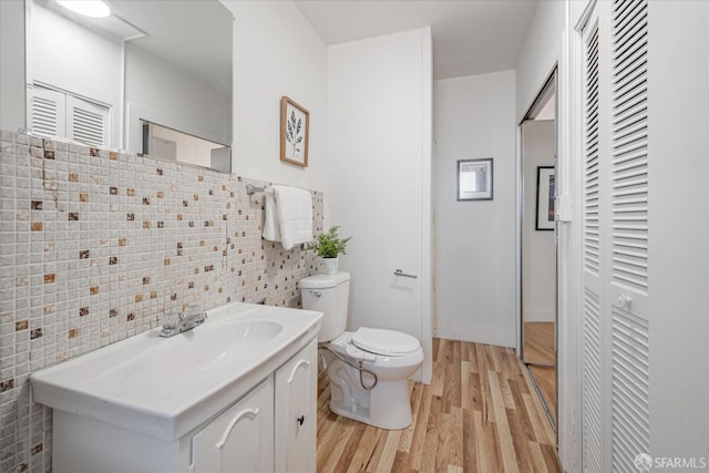 half bath featuring vanity, toilet, and wood finished floors