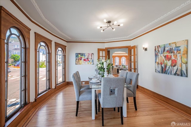 dining area with ornamental molding, a chandelier, light wood-style flooring, and baseboards