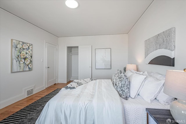 bedroom featuring a closet, visible vents, baseboards, and wood finished floors