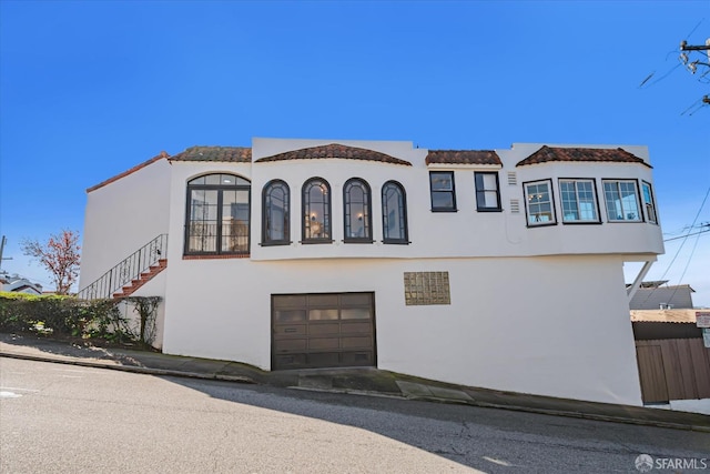 view of front facade featuring stairway, an attached garage, and stucco siding