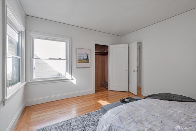 bedroom featuring light wood finished floors, a closet, and baseboards