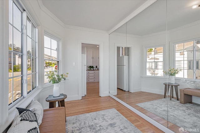 living area with light wood-style flooring, baseboards, and crown molding