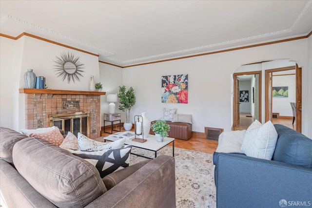 living area featuring a glass covered fireplace, visible vents, and crown molding