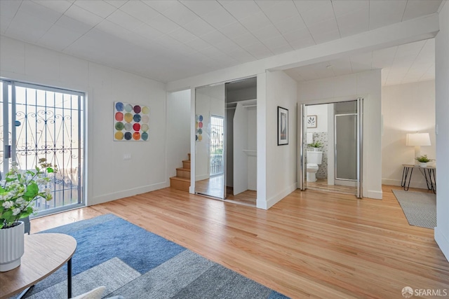 foyer with light wood finished floors, baseboards, and stairway