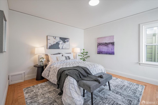 bedroom featuring light wood-style flooring, visible vents, and baseboards