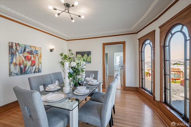 dining room featuring ornamental molding, baseboards, light wood finished floors, and an inviting chandelier