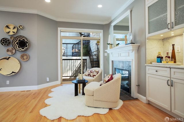 living area featuring plenty of natural light, light hardwood / wood-style floors, and crown molding