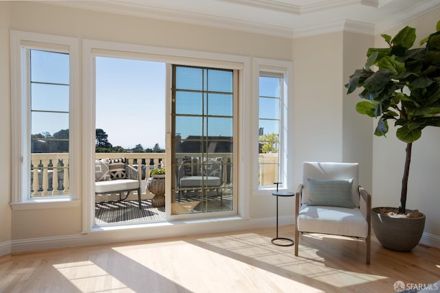 living area with crown molding, a wealth of natural light, and light hardwood / wood-style floors