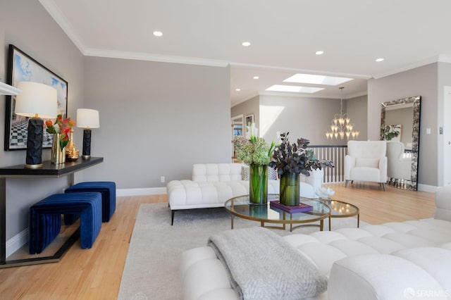 living room featuring a skylight, light wood-type flooring, crown molding, and an inviting chandelier