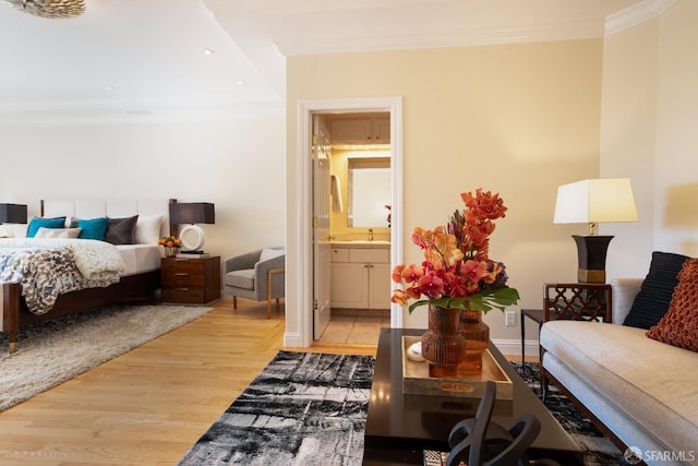 bedroom featuring ornamental molding, light wood-type flooring, and connected bathroom