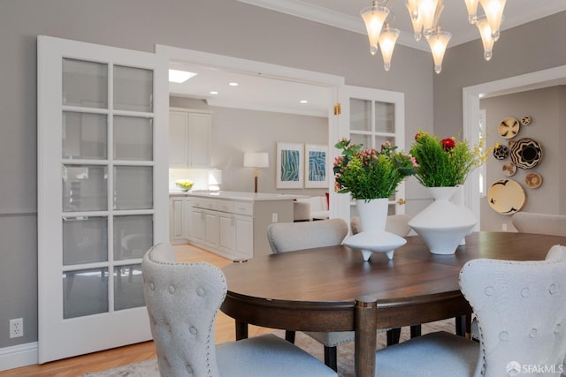 dining area featuring a chandelier, light hardwood / wood-style floors, and crown molding