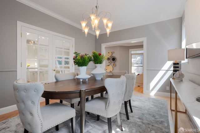 dining space featuring an inviting chandelier, light hardwood / wood-style flooring, and crown molding