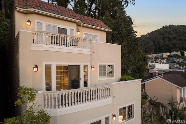 back house at dusk featuring a balcony