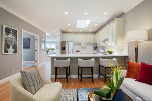 kitchen with stainless steel fridge, crown molding, tasteful backsplash, and a breakfast bar