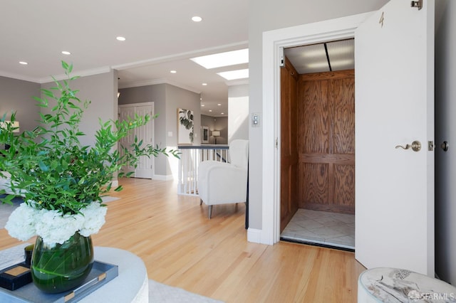 interior space with a skylight, light wood-type flooring, and crown molding