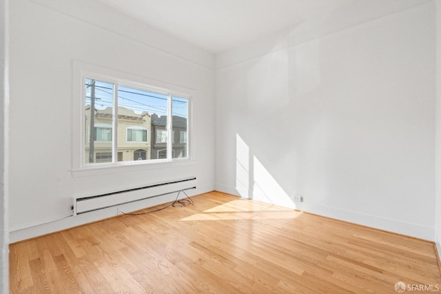 empty room featuring baseboard heating and hardwood / wood-style flooring