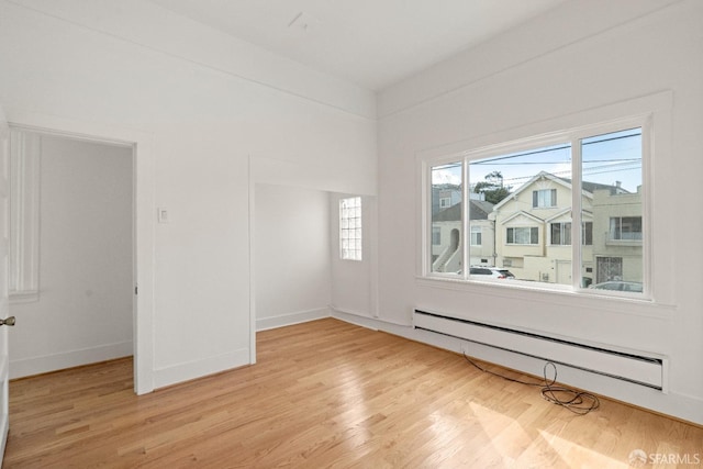 spare room with a baseboard radiator and light wood-type flooring