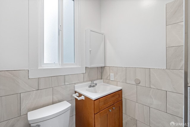 bathroom with vanity, toilet, and tile walls