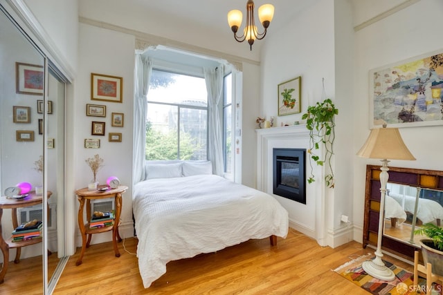 bedroom with light wood-type flooring, an inviting chandelier, and a closet