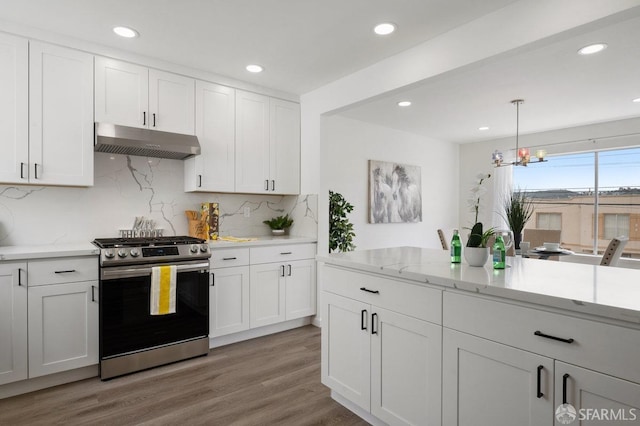 kitchen with decorative light fixtures, gas range, white cabinets, and range hood