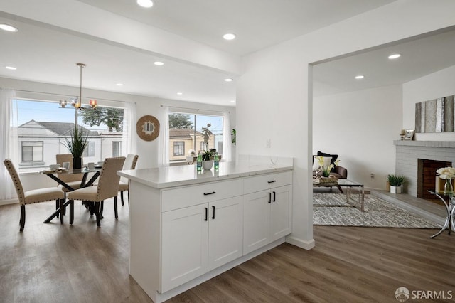 kitchen featuring a notable chandelier, white cabinetry, decorative light fixtures, dark wood-type flooring, and a fireplace