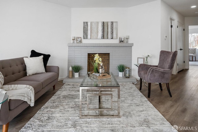 living room with dark hardwood / wood-style flooring and a brick fireplace