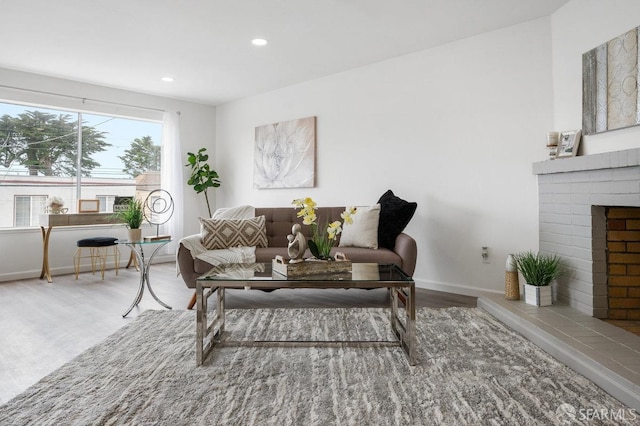 living room with a brick fireplace and wood-type flooring