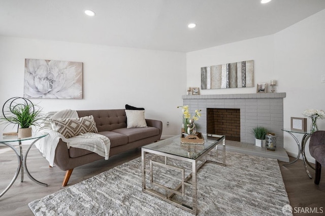 living room with a brick fireplace and wood-type flooring