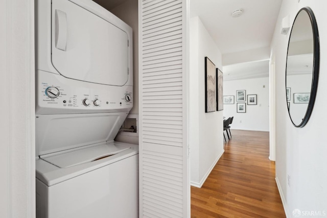 laundry room featuring laundry area, light wood-style flooring, baseboards, and stacked washer and clothes dryer