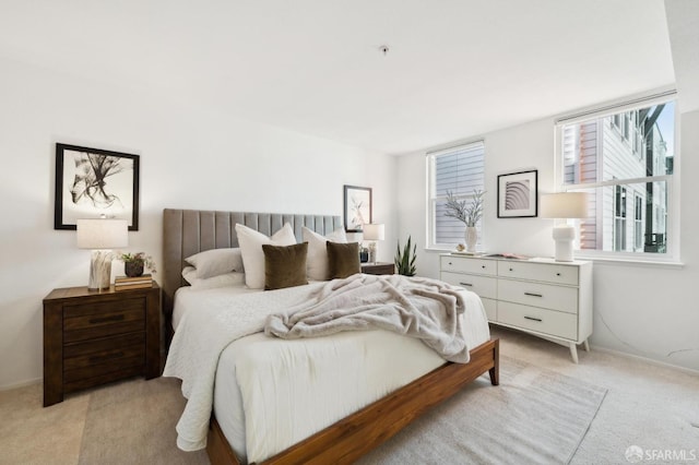 bedroom featuring baseboards, multiple windows, and light carpet