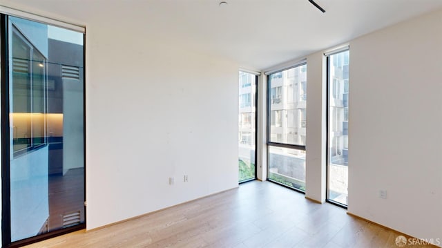 unfurnished room featuring floor to ceiling windows and light hardwood / wood-style floors