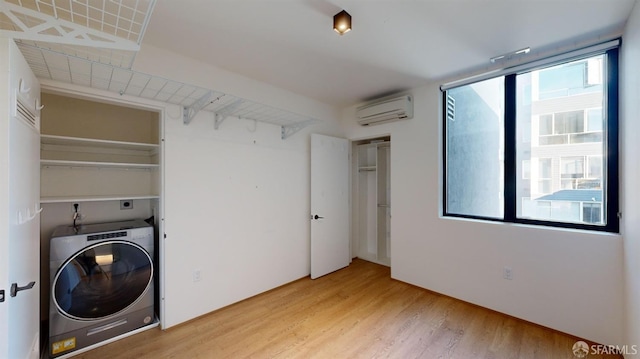 washroom featuring washer / dryer, an AC wall unit, plenty of natural light, and wood-type flooring