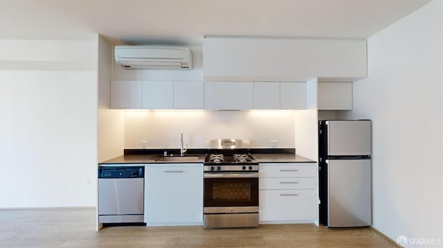 kitchen featuring white cabinets, sink, a wall mounted AC, light hardwood / wood-style floors, and stainless steel appliances