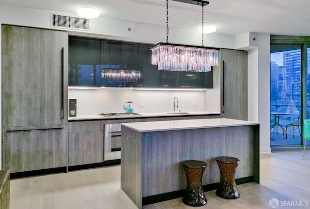 kitchen featuring pendant lighting, sink, a center island, stainless steel gas cooktop, and paneled built in fridge