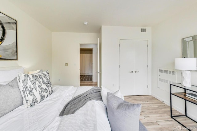 bedroom with radiator, a closet, and light wood-type flooring