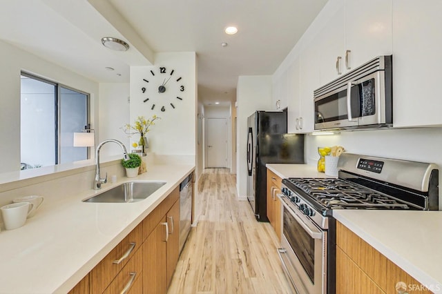 kitchen with white cabinetry, sink, stainless steel appliances, and light wood-type flooring