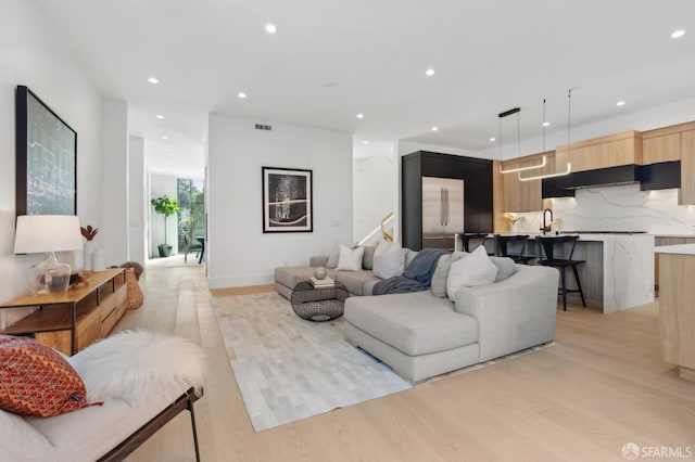 living room featuring light wood-type flooring, visible vents, and recessed lighting