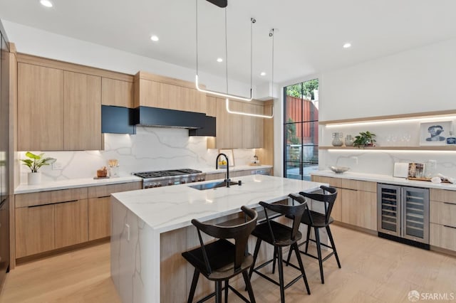 kitchen with wine cooler, range hood, open shelves, an island with sink, and a kitchen breakfast bar