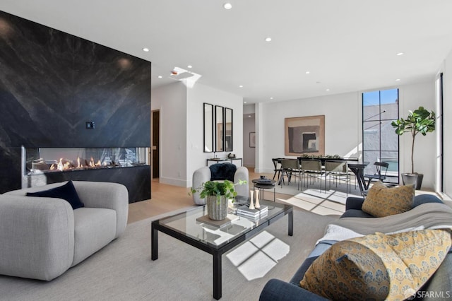 living room with light wood-type flooring, recessed lighting, a lit fireplace, and baseboards