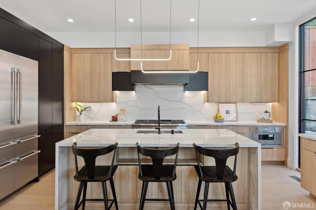 kitchen featuring pendant lighting, a center island with sink, modern cabinets, light stone countertops, and built in refrigerator