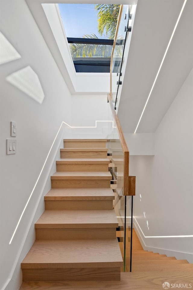 stairway with a skylight and baseboards