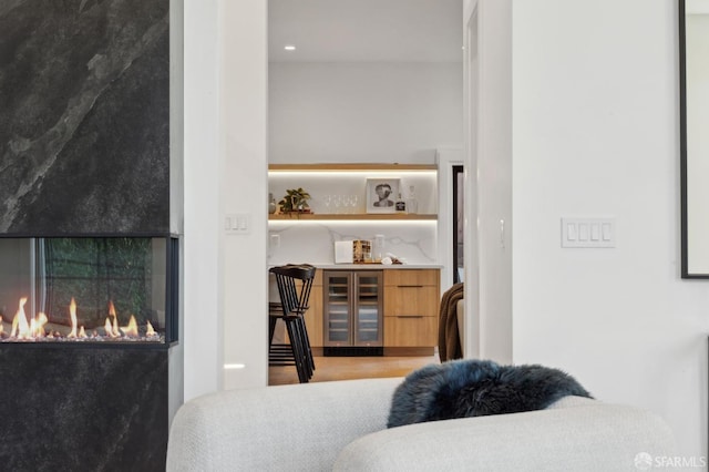 bedroom with beverage cooler and a glass covered fireplace