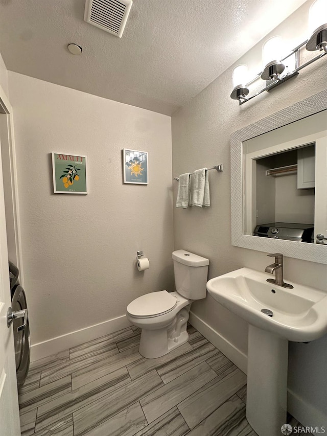 139 Hall Ln, Walnut Creek, CA 94597 - half bathroom featuring toilet, baseboards, a textured ceiling, wood tiled floors, and a sink