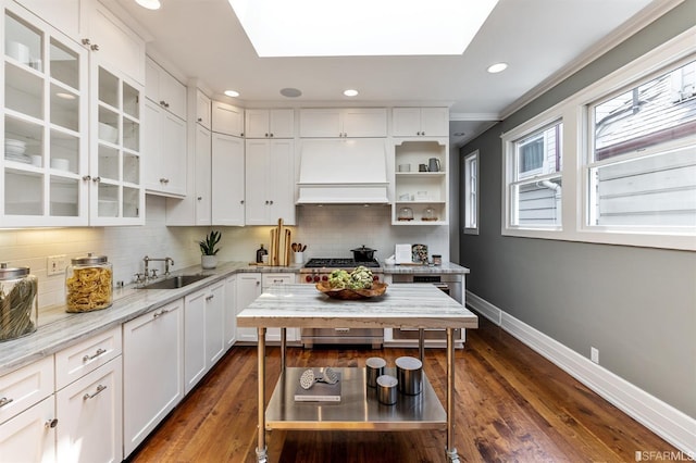 kitchen featuring sink, white cabinetry, high end stainless steel range oven, light stone countertops, and decorative backsplash