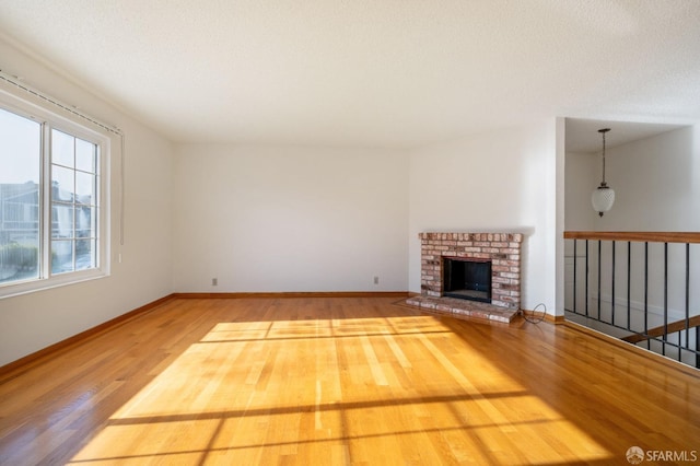 unfurnished living room with wood-type flooring and a brick fireplace