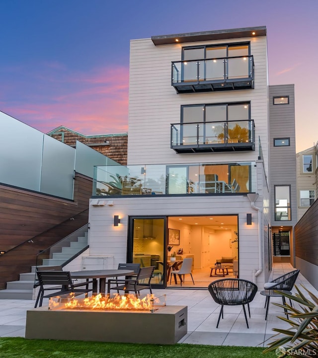 back of house featuring a patio, a fire pit, a balcony, and stairs